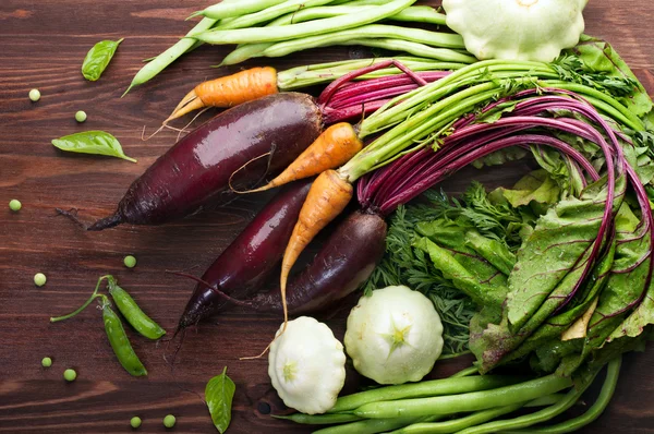 Vegan concept. Harvesting. Juicy fresh vegetables, such as carrots, beets, green beans and patisony on a brown wooden background. The organic low-calorie fresh vegetables