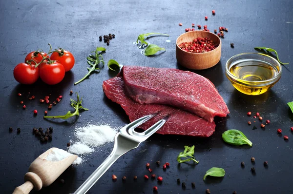 Raw beef steak on dark board. Backlight. The concept of preparing meat for cooking steaks