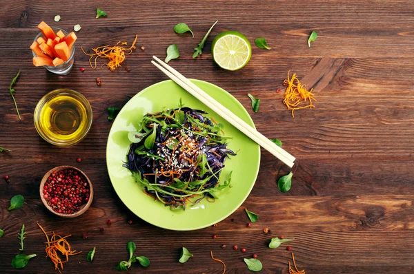 Concept diet food. Delicious vegetarian salad of arugula, leaf mash, purple cabbage and carrots on a brown wooden background. Natural organic healthy food, ready-to-eat