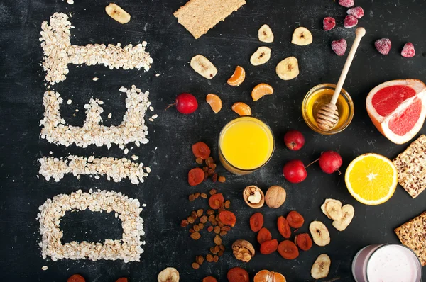 Concept diet food. Fruits, dried fruits, nuts, orange juice and honey on a black background. Left the word \