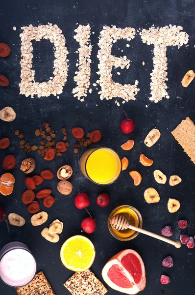 Concept diet food. Fruits, dried fruits, nuts, orange juice and honey on a black background. Above the word \