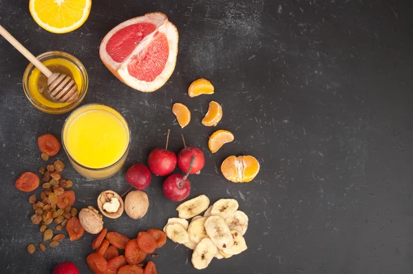 Concept diet food. Fruits, dried fruits, nuts, orange juice and honey on a black background. Place for writing text or a prescription diet.