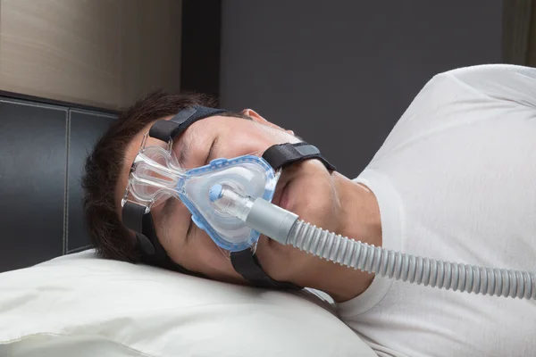 Asian man with sleep apnea using CPAP machine