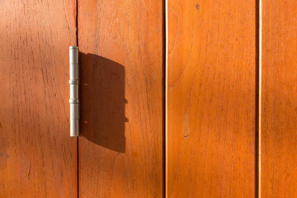 Wood panel with metal hinge in afternoon light