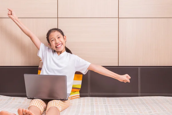 Happy smiling and excited asian girl using computer laptop noteb