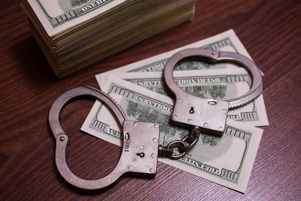 Money and the law, handcuffs on money, 100 dollar bills back side and handcuffs