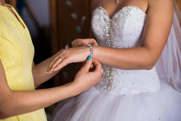 Girl wears a bracelet on a hand of the bride, bride\'s morning, preparing for the wedding