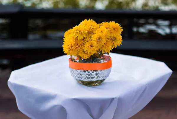 Bouquet of yellow orange flowers stands in a jug on the table, wedding flowers