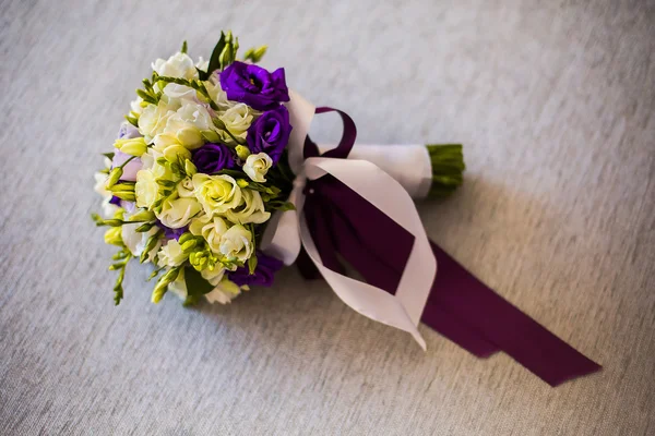 Bridal bouquet of white and blue flowers, rings, purple butterfly and invitation-cards lie on a light background, preparations for the wedding, the groom\'s fees
