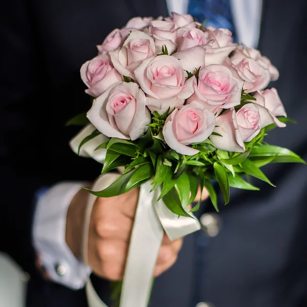 Wedding flowers, groom holds bouquet of pink roses