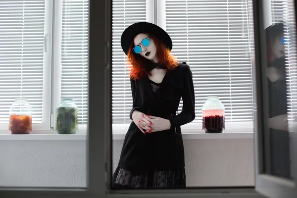 Portrait of red-haired girl in bow tie on a dark background, gothic style girl in black clothes