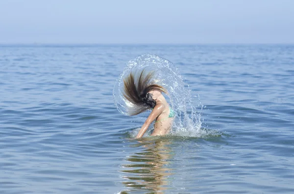 Beauty Model Girl Splashing Water with her Hair. Teen girl Swimming and splashing on summer beach over sunset. Beautiful Woman in Water. Summer holidays at sea