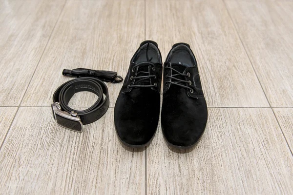 Black bow tie and leather shoes groom lying next to belt of trousers. Groom accessories, businessman,
