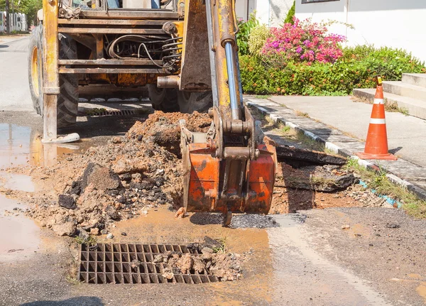 Excavator working on the Repair of  pipe water and sewerage on road