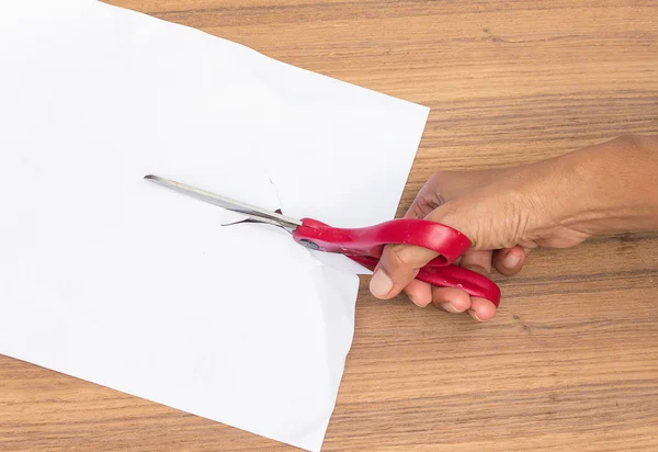 Scissors cut paper on a wooden table.