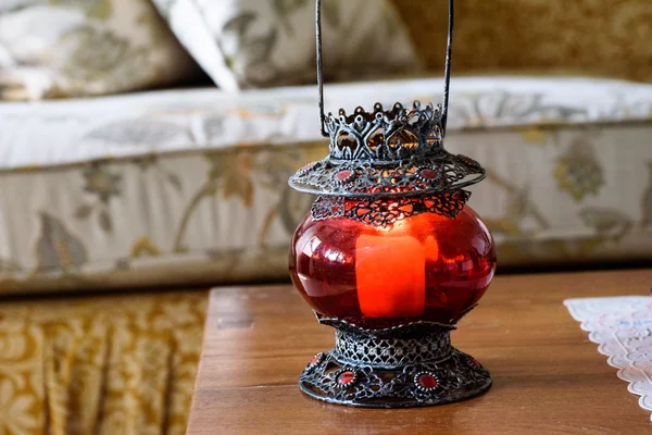 Lighted candle in red lamp at the center table