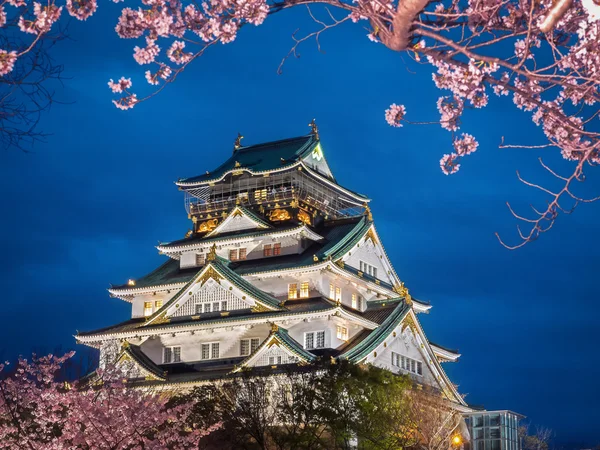 Osaka castle among cherry blossom trees (sakura) in the evening