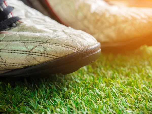 Old muddy dirty football shoes on artificial grass with copy space