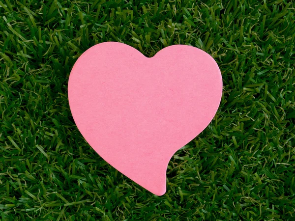 Pink heart-shaped notpad on the artificial grass