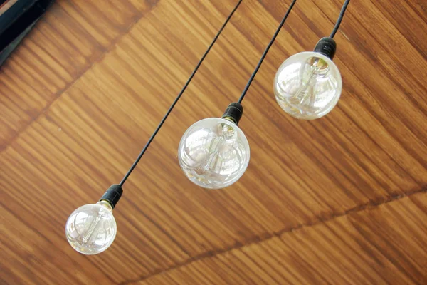 Three retro light bulbs hanging from wood ceiling in coffee shop