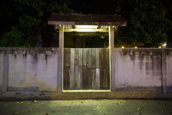 Old wood gate and cement wall in night time in suburban district, Thailand