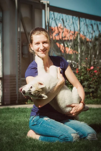 Woman with smiling siberian husky dog, sitting on a sunny day, on a walk with dog