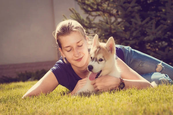 Woman with smiling siberian husky dog, sitting on a sunny day, on a walk with dog