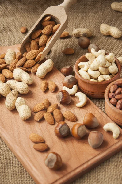 Almonds, cashew and hazelnuts in wooden bowls on wooden and burlap background