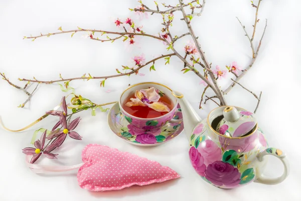 Heart-shaped pillow, blooming almond tree branch, tea-cup and te