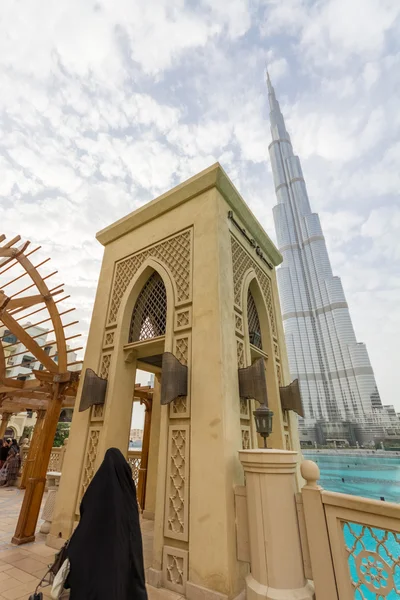 Woman in burka, classical tower and Burj Khalifa Tower, Dubai