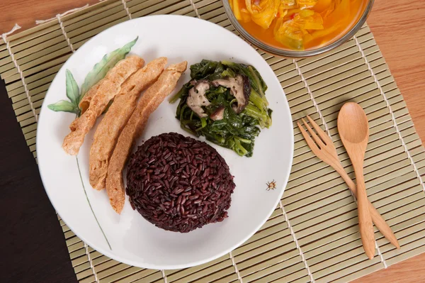 Vegetarian food Thai-style with Stir-fried vegetables spinac and shiitake, Riceberry rice, tamarind paste and sour soup (Selective Focus, Focus on the Riceberry rice)