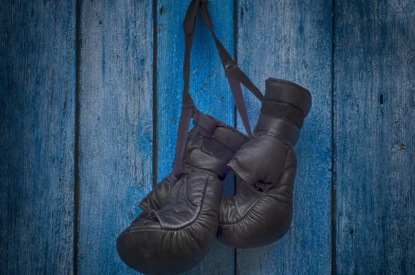 Pair of black gloves for Thai boxing hanging on a nail