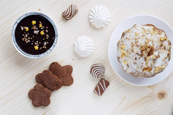 Cake with a glaurye and walnuts, handwork cookies, chocolates, a cottage cheese dessert, meringue, close up, the top view on a wooden table