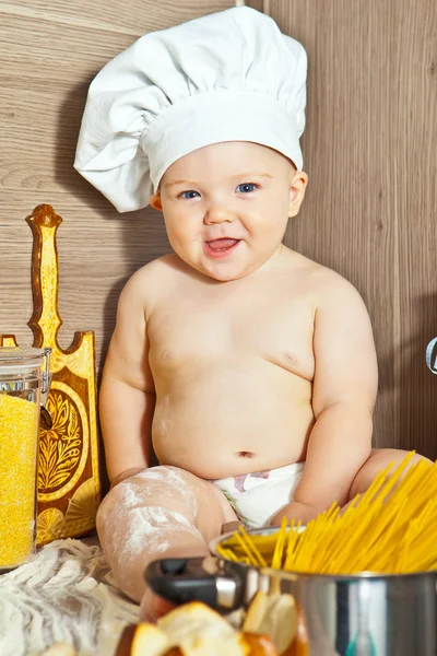 Little happy boy kid play in chef at kitchen and cook food