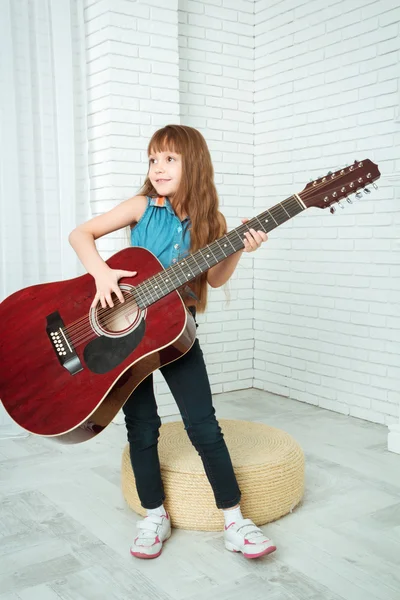 Little girl stands with a guitar