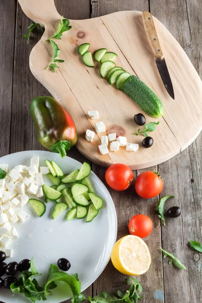 Cooking Greek salad, cutting a cucumber