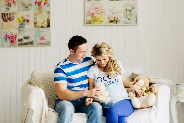 Couple with pregnant woman relaxing on sofa together.