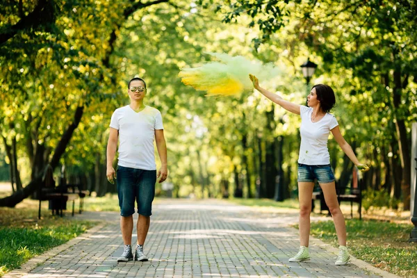 Young and beautiful, hipster couple playing in the park on holi color festival with colour paint powder.