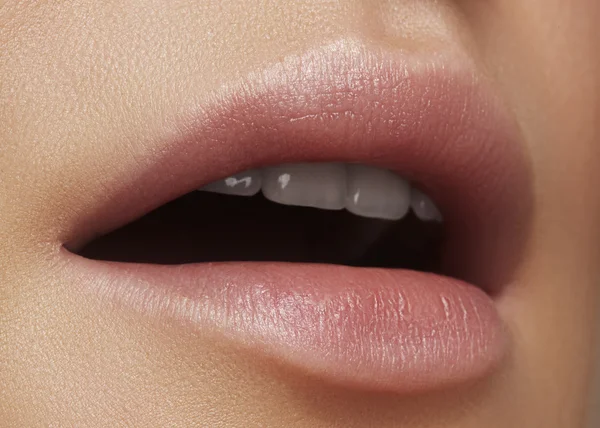 Close-up beautiful female lips with bright lipgloss makeup. Perfect clean skin, light fresh lip make-up. Beautiful spa macro shot with tender pink lip gloss. Spa and cosmetics