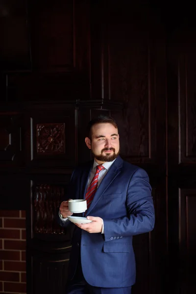 Rich successful handsome man in a suit drinking coffee