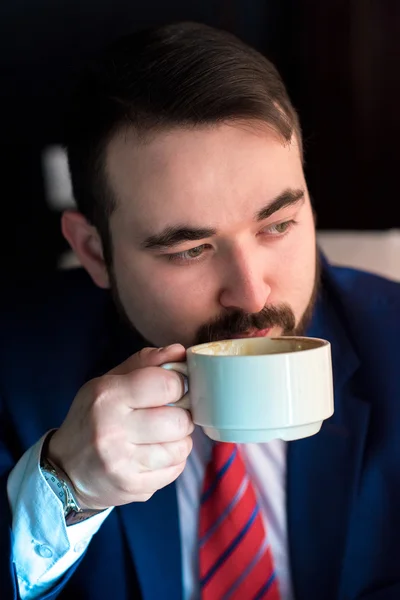 Rich successful handsome man in a suit drinking coffee