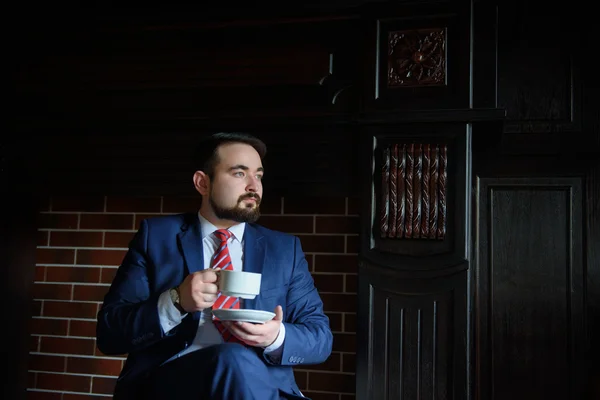 Rich successful handsome man in a suit drinking coffee