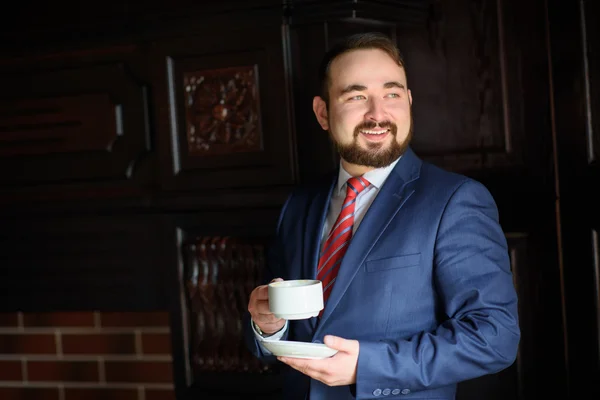 Rich successful handsome man in a suit drinking coffee