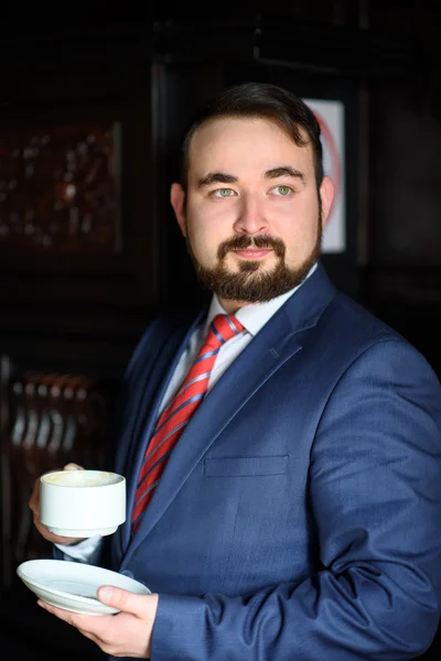 Rich successful handsome man in a suit drinking coffee