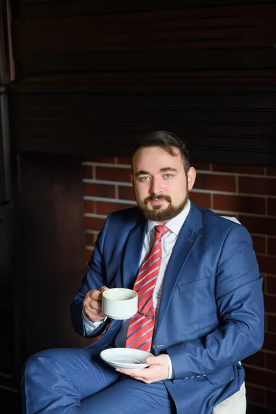 Rich successful handsome man in a suit drinking coffee