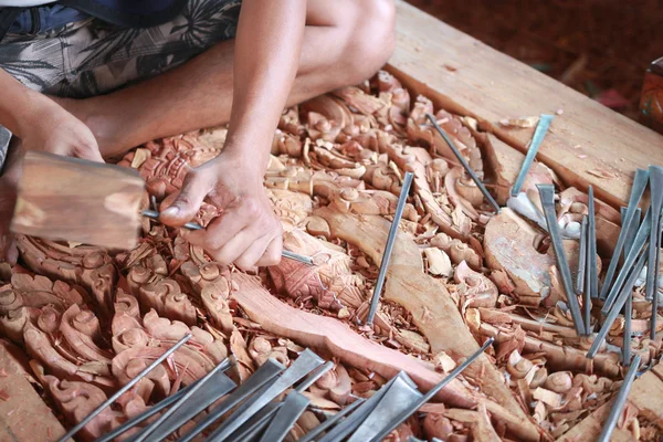 Traditional craftsman carving wood with buddha image