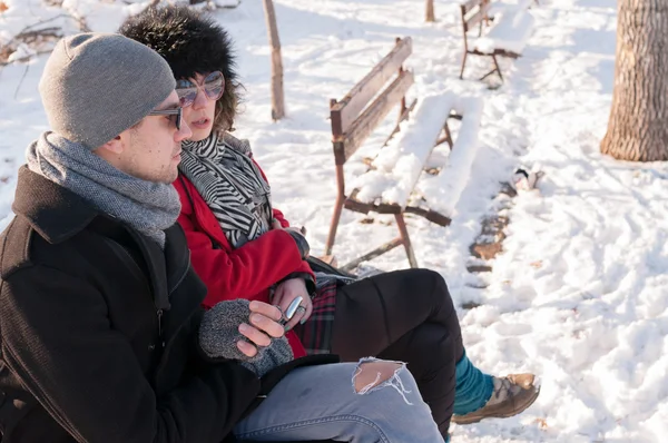 Young couple sitting on bench in winter