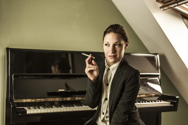 Young woman in men\'s black suit smoking cigarette sensual near a