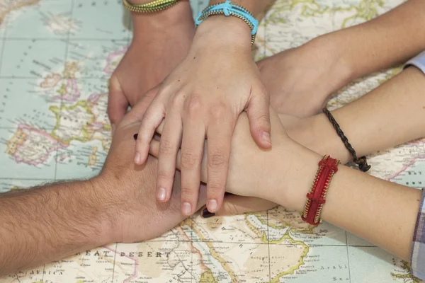 Family hands together over a world map. Team concept.