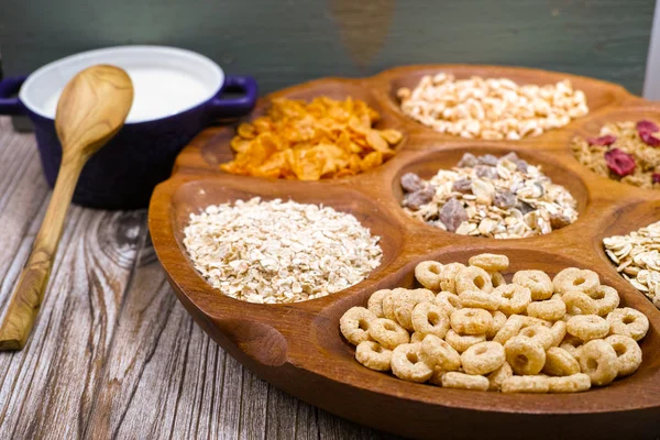 Wooden bowl with mixed breakfast cereals and blue bowl with fres